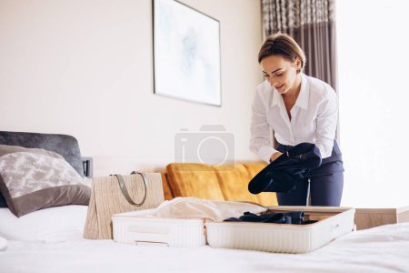 Photo for Business woman packing bag in her hotel room - Royalty Free Image