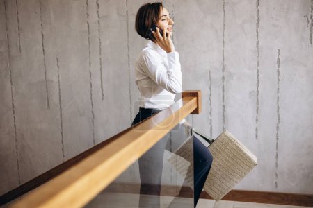 Téléchargez les photos : Femme d'affaires monter les escaliers de la chambre d'hôtel et parler au téléphone - en image libre de droit