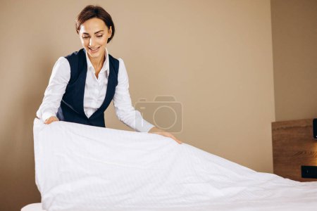 Téléchargez les photos : Femme femme de ménage préparant des draps dans la chambre d'hôtel - en image libre de droit