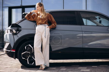 Photo for Business woman charging electric car - Royalty Free Image