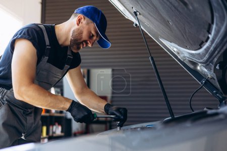 Téléchargez les photos : Mécanicien de voiture travaillant sur l'atelier de réparation de service automobile - en image libre de droit