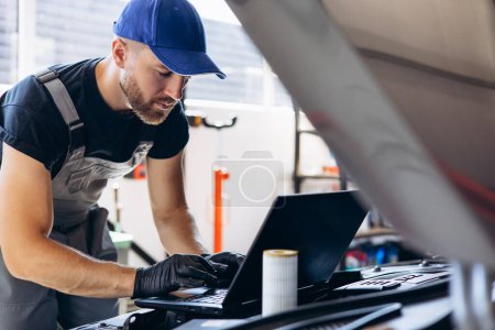 Photo for Car mechanic having car diagnostics on his laptop - Royalty Free Image
