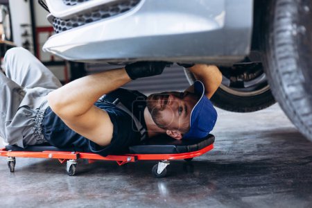 Photo for Car mechanic doing car check up under the auto - Royalty Free Image
