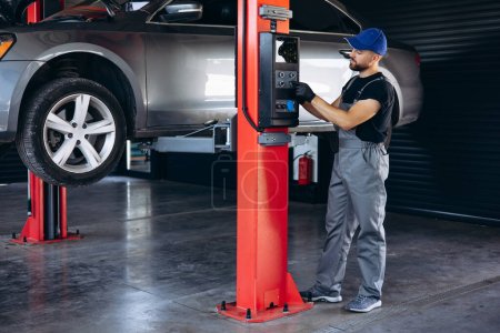 Photo for Auto mechanic lifting car and doing check up on car service - Royalty Free Image