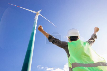 Photo for Woman engineer with helmet standing by the windmill turbines - Royalty Free Image