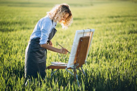 Foto de Mujer artista pintura con pinturas al óleo en un campo - Imagen libre de derechos