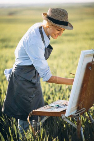 Foto de Mujer artista pintura con pinturas al óleo en un campo - Imagen libre de derechos