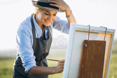 Téléchargez les photos : Peinture de femme artiste avec des peintures à l'huile dans un champ - en image libre de droit