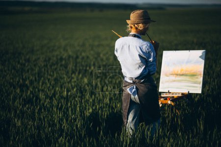 Téléchargez les photos : Peinture de femme artiste avec des peintures à l'huile dans un champ - en image libre de droit