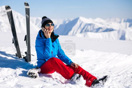 Téléchargez les photos : Femme skiant dans les montagnes et parlant au téléphone - en image libre de droit