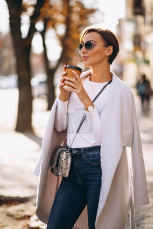 Téléchargez les photos : Femme portant un manteau et buvant du café - en image libre de droit