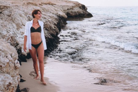 Téléchargez les photos : Belle femme en bikini posant au bord de l'océan - en image libre de droit