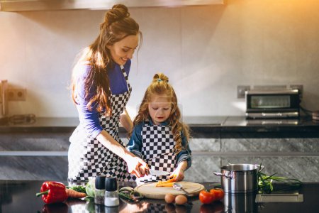 Téléchargez les photos : Mère et fille cuisinent à la maison - en image libre de droit