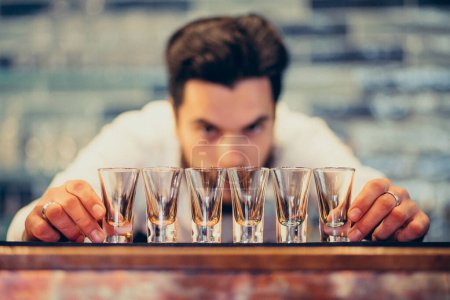 Téléchargez les photos : Beau barman faisant boire et cocktails à un comptoir - en image libre de droit