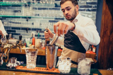 Téléchargez les photos : Beau barman faisant boire et cocktails à un comptoir - en image libre de droit