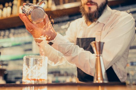 Photo for Handsome bartender making drinking and cocktails at a counter - Royalty Free Image