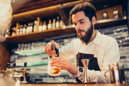 Foto de Camarero guapo haciendo bebidas y cócteles en un mostrador - Imagen libre de derechos