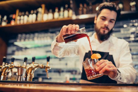 Foto de Camarero guapo haciendo bebidas y cócteles en un mostrador - Imagen libre de derechos