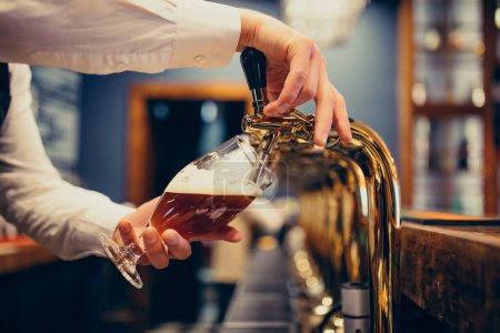 Téléchargez les photos : Homme barman verser de la bière dans un pub - en image libre de droit