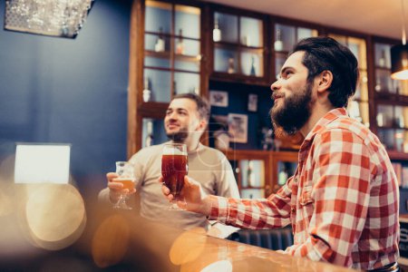 Foto de Dos guapos barbudos bebiendo cerveza en el pub - Imagen libre de derechos