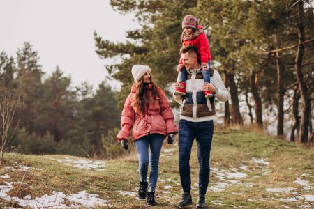 Téléchargez les photos : Jeune famille marchant ensemble dans la forêt en hiver - en image libre de droit