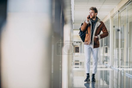 Foto de Joven hombre guapo en el aeropuerto hablando por teléfono - Imagen libre de derechos