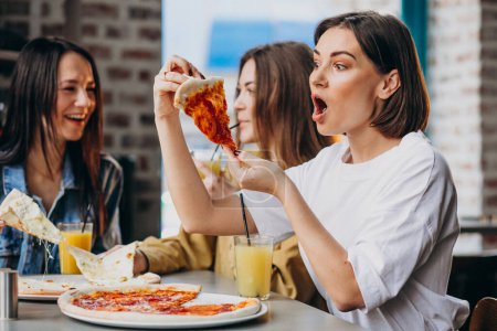 Foto de Tres amigas tomando pizza en un bar - Imagen libre de derechos