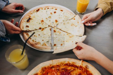 Téléchargez les photos : Trois amies qui mangent de la pizza dans un bar - en image libre de droit