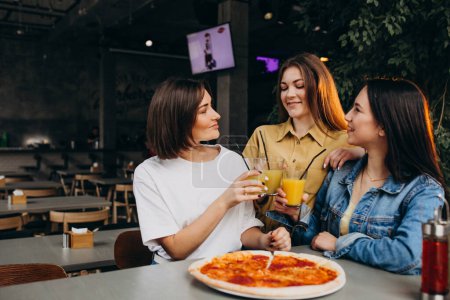 Foto de Chicas amigas comiendo pizza en un bar a la hora del almuerzo - Imagen libre de derechos