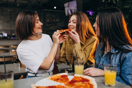 Photo for Girls friends having pizza at a bar at a lunch time - Royalty Free Image