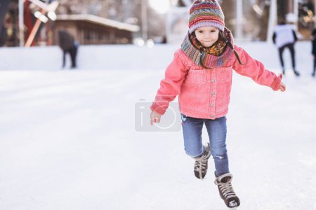 Téléchargez les photos : Petite fille mignonne patinant sur une patinoire dans le centre-ville - en image libre de droit