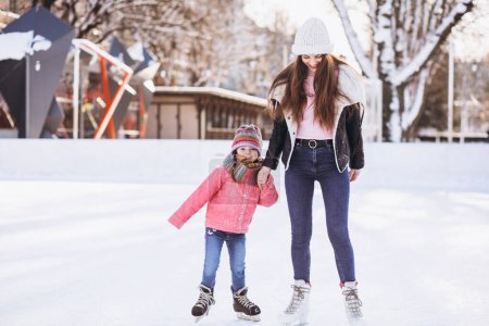 Photo for Mother with daughter teaching ice skating on a rink - Royalty Free Image