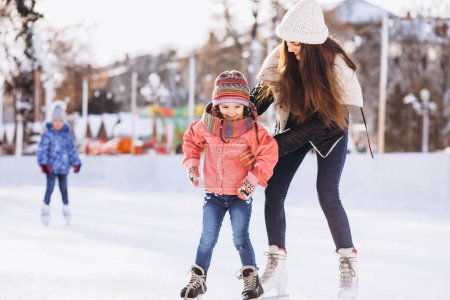 Mother with daughter teaching ice skating on a rink