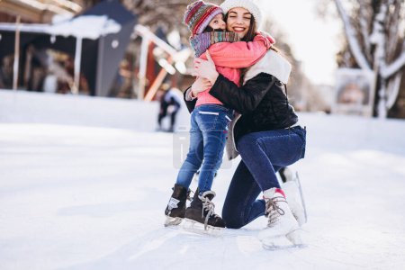 Madre con hija enseñando patinaje sobre hielo en una pista