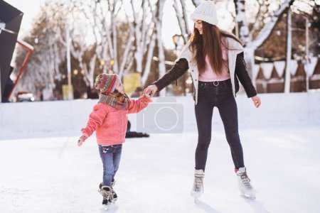 Téléchargez les photos : Mère avec sa fille enseignant le patinage sur une patinoire - en image libre de droit