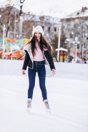 Téléchargez les photos : Jeune femme patinant sur une patinoire dans un centre-ville - en image libre de droit