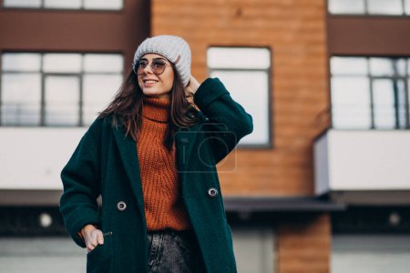 Photo for Young pretty woman in warm coat by the house - Royalty Free Image