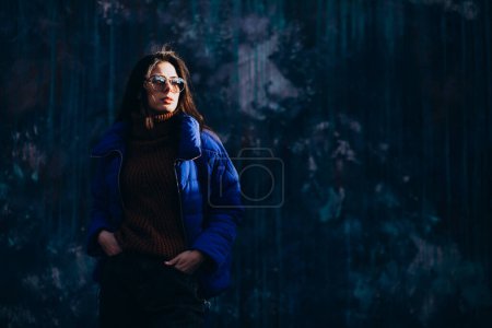 Téléchargez les photos : Jeune femme modèle en veste d'hiver bleue sur fond bleu - en image libre de droit