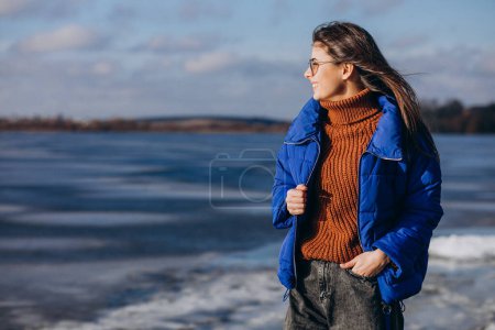 Foto de Mujer joven viajera en chaqueta azul junto al lago - Imagen libre de derechos