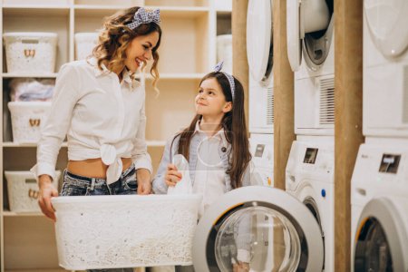 Foto de Madre con hija haciendo la colada en la lavandería de auto servicio - Imagen libre de derechos