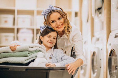 Foto de Madre con hija haciendo la colada en la lavandería de auto servicio - Imagen libre de derechos
