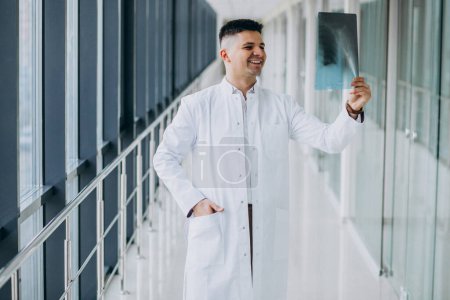 Téléchargez les photos : Jeune beau chirurgien regardant la radiographie - en image libre de droit