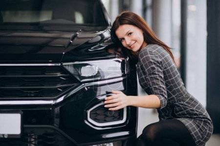 Photo for Young woman in a car showroom choosing a car - Royalty Free Image