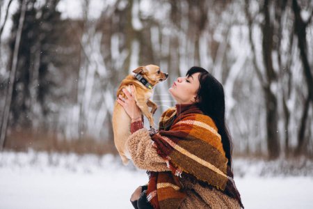 Téléchargez les photos : Jeune femme à l'extérieur du parc avec son petit chien en hiver - en image libre de droit