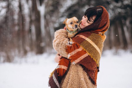Téléchargez les photos : Jeune femme à l'extérieur du parc avec son petit chien en hiver - en image libre de droit