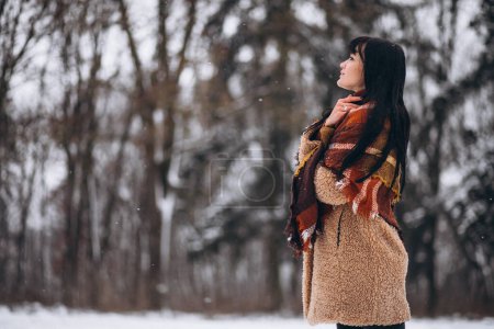 Téléchargez les photos : Jeune femme heureuse en chiffons chauds dans un parc d'hiver - en image libre de droit