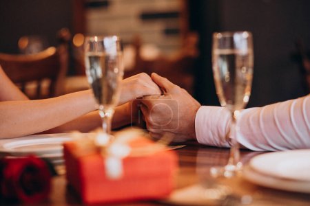 Photo for Couple holding hands on valentines evening in a restaurant - Royalty Free Image