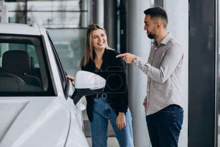 Photo for Young couple choosing a car in a car show room - Royalty Free Image