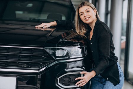 Photo for Young woman hugging a car in a car showroom - Royalty Free Image