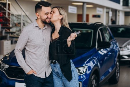 Téléchargez les photos : Jeune couple choisissant une voiture dans une salle d'exposition de voiture - en image libre de droit